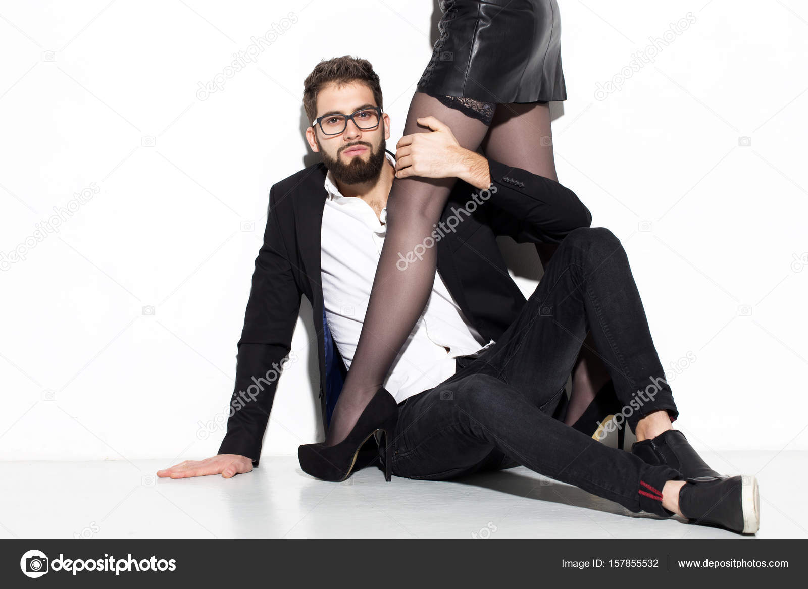 Rijke stijlvolle man omarmen de benen van de vrouw op hoge hakken