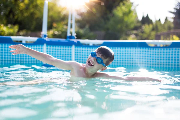 Niño feliz nadando en la piscina al aire libre color puesta de sol graduada —  Fotos de Stock