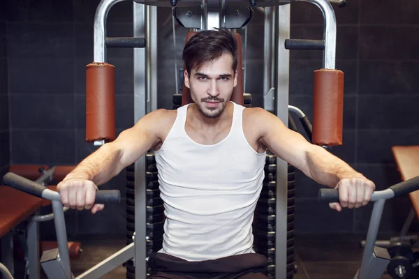 Jonge man training in de sportschool door op te drukken machine — Stockfoto