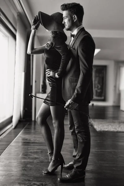 Dominantní bohatý mladík s bičem všeobjímající milence černé a bílé — Stock fotografie