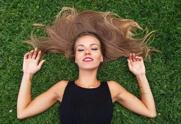 Giovane donna spensierata sdraiata nell'erba e sognando — Foto Stock