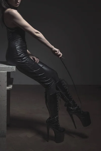 Sexy dominatrix commanding to high heel boots by whip — Stock Photo, Image