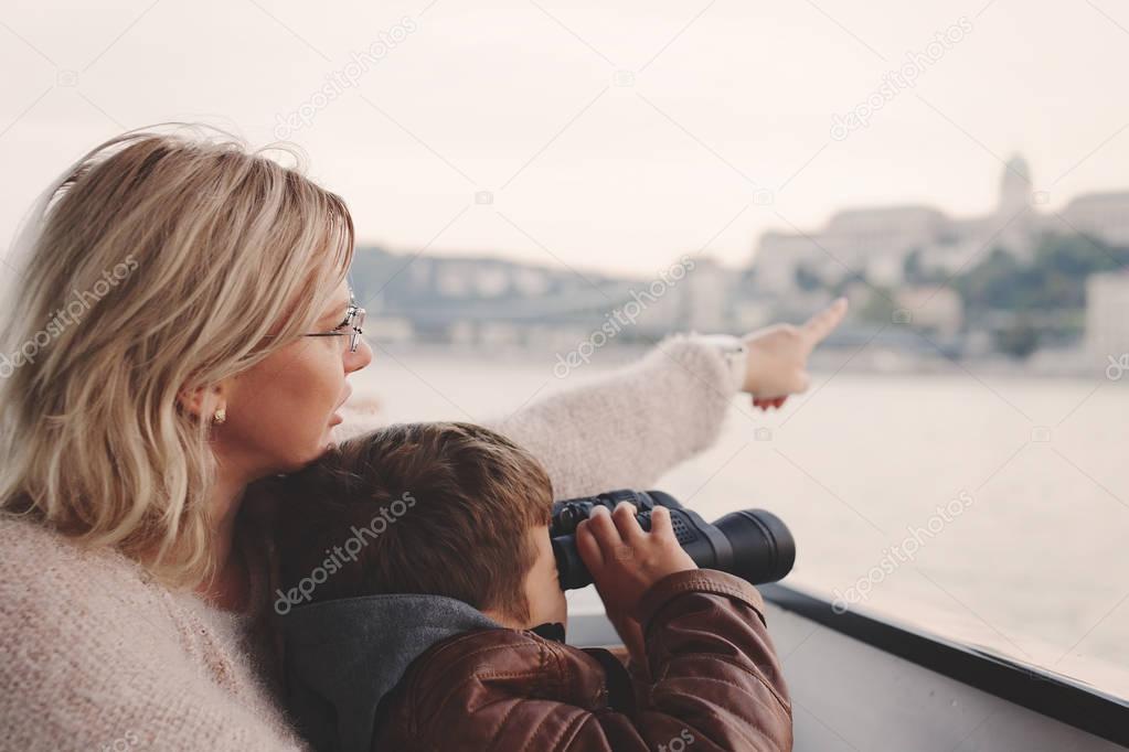 Mother showing away to son with binoculars looking, gazing, sear