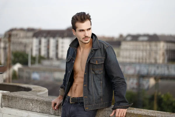 Sexy homem na moda em jeans posando ao ar livre na cidade — Fotografia de Stock