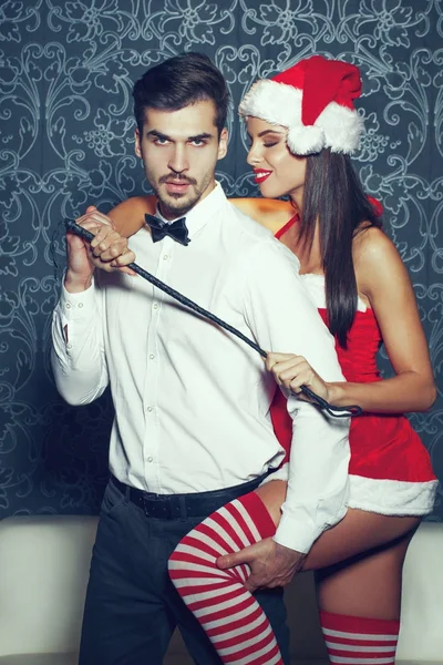 Sexy Santa donna giocare con uomo ricco da frusta a Natale — Foto Stock