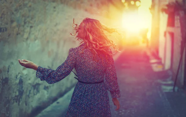 Young carefree woman walking on mediterranean street in sunset — Stock Photo, Image