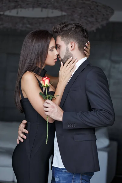 Joven mujer rica besando hombre con rosa — Foto de Stock