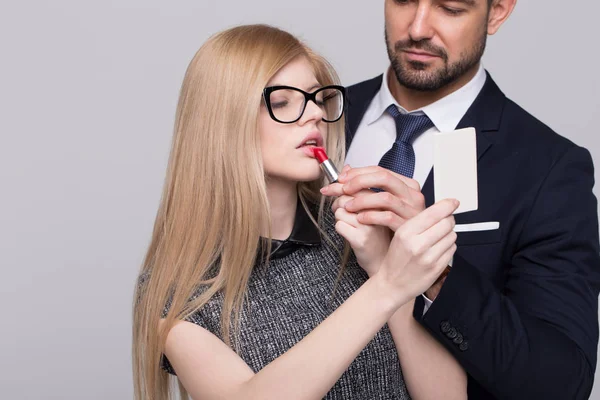 Femme fatale woman applying red lipstick with mans helping hand — Stock Photo, Image
