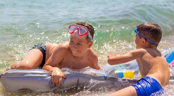 Små pojkar leker i havet på luft vatten madrass — Stockfoto