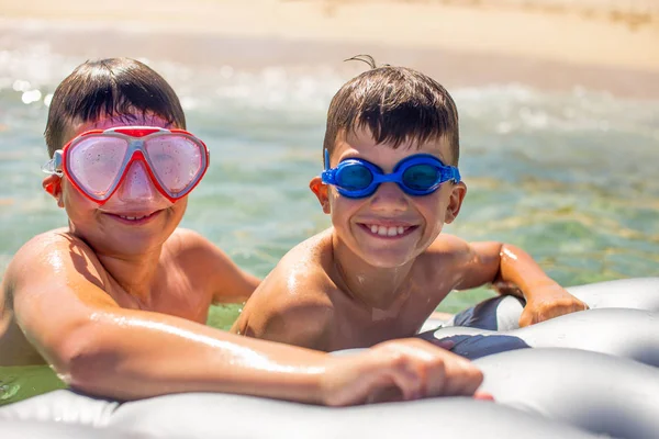 Happy little boys in goggles on air water mattress in sea toothy — Stock Photo, Image