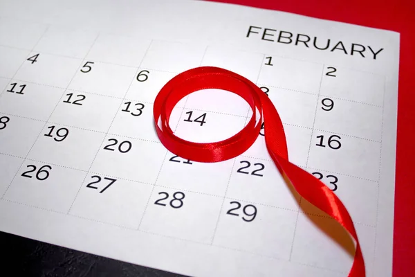 calendar on the table, February 14 highlighted with red ribbon