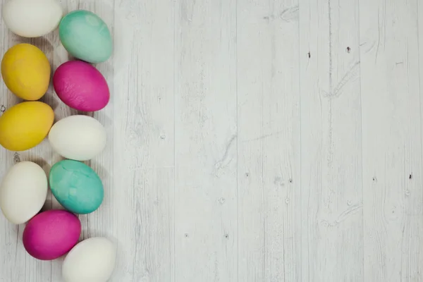 Fundo de Páscoa com ovos de Páscoa coloridos em mesa cinza de madeira . — Fotografia de Stock