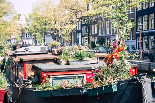Симпатичные домики на амстердамских каналах со старой лодкой впереди — стоковое фото