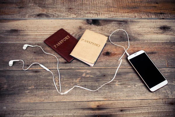 The white smartphone with earphones and two passports on a woode