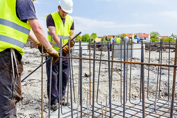 Trabajadores de la construcción atando barras de refuerzo para reforzar columna de hormigón — Foto de Stock