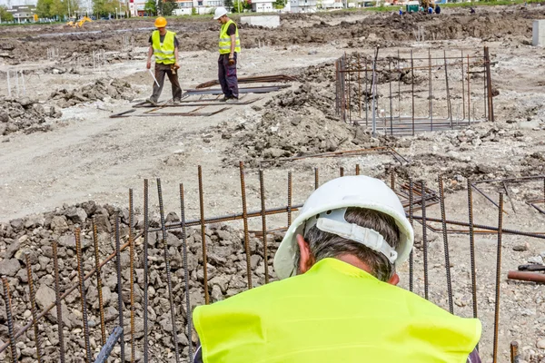 Trabajadores de la construcción atando barras de refuerzo para reforzar columna de hormigón — Foto de Stock