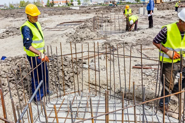 Trabalhadores da construção que ligam vergalhões para reforçar coluna de concreto — Fotografia de Stock