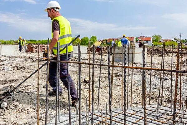 Trabalhadores da construção que ligam vergalhões para reforçar coluna de concreto — Fotografia de Stock