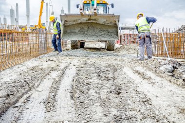 İşçiler beton Ekskavatör'ın fron üzerinden kürek ile boşaltma