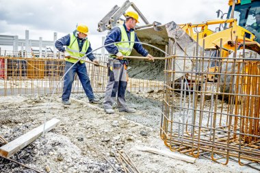 İşçiler beton Ekskavatör'ın fron üzerinden kürek ile boşaltma