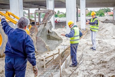 İşçiler beton Ekskavatör'ın fron üzerinden kürek ile boşaltma