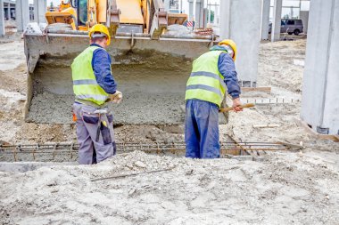 İşçiler beton Ekskavatör'ın fron üzerinden kürek ile boşaltma
