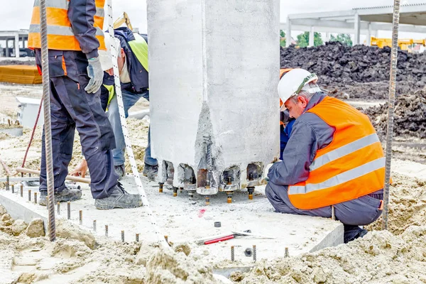 Vista en el sitio de construcción hasta que los trabajadores son montaje pilar de hormigón — Foto de Stock