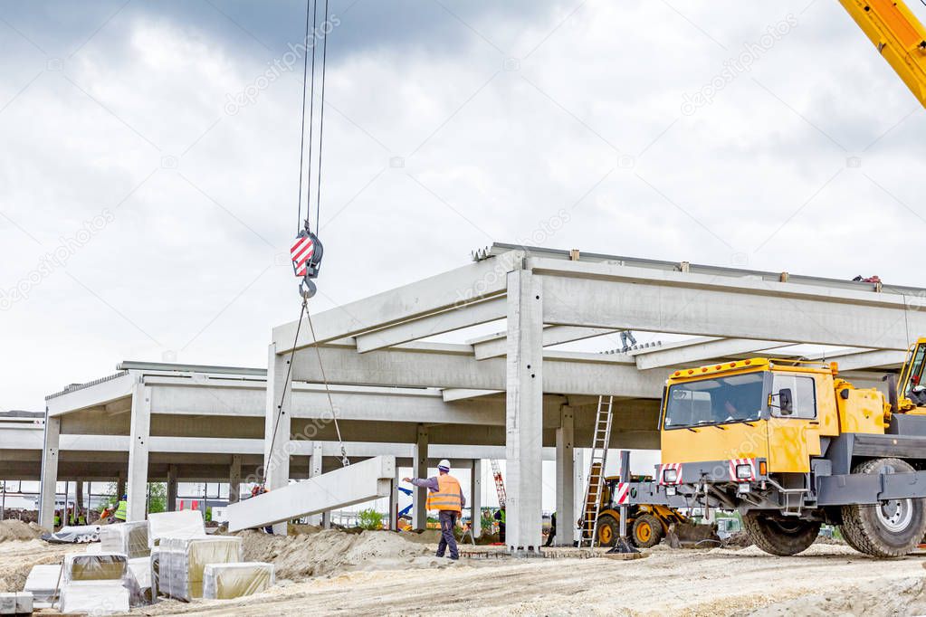 Mobile crane is unloading concrete joist from truck trailer to a