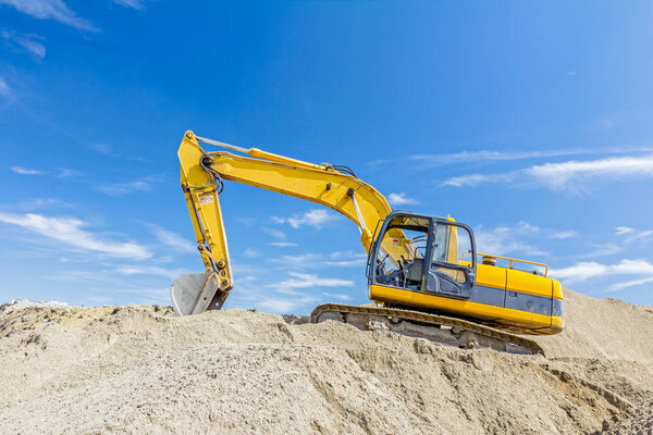 Excavator is preparing pile of sand for loading in truck on buil