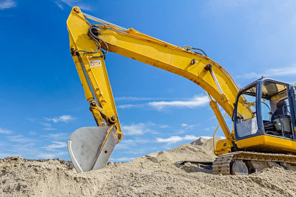 Excavator is preparing pile of sand for loading in truck on buil
