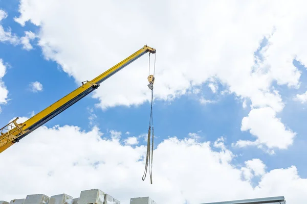 Crane hook with straps is hanging above building site — Stock Photo, Image