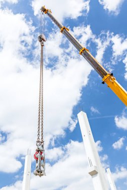 Vinç kanca yukarıda zincirleri üzerinde sallanan, bulutlu gökyüzü arka planda