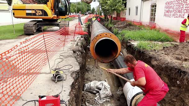 Worker is cleaning pipe out of mud with a shovel — Stock Video