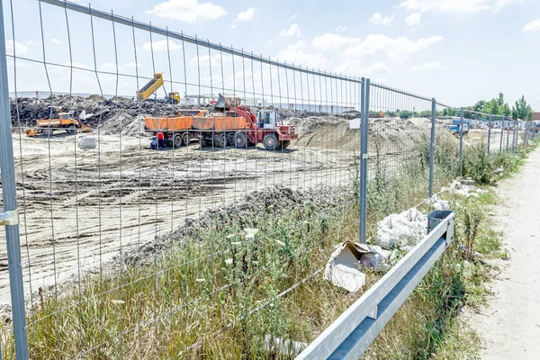 Bulldozer is het laden van een vrachtwagen op de bouwplaats in omheind terrein — Stockfoto