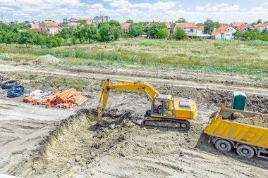 Ekskavatör bir siper kazma ve sı binasında bir kamyon yükleme