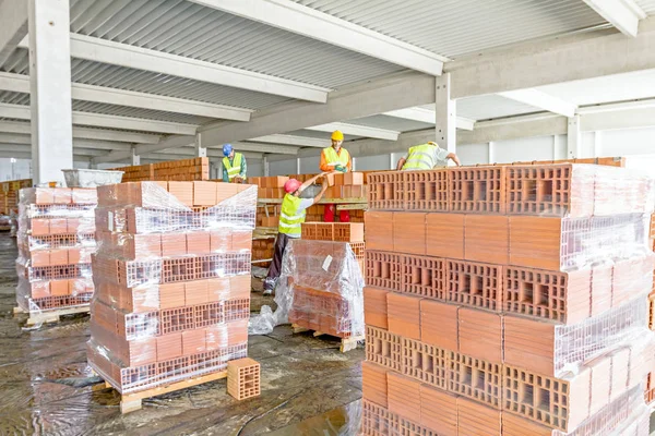 Bauarbeiter bauen Trennwand mit roten Blöcken — Stockfoto