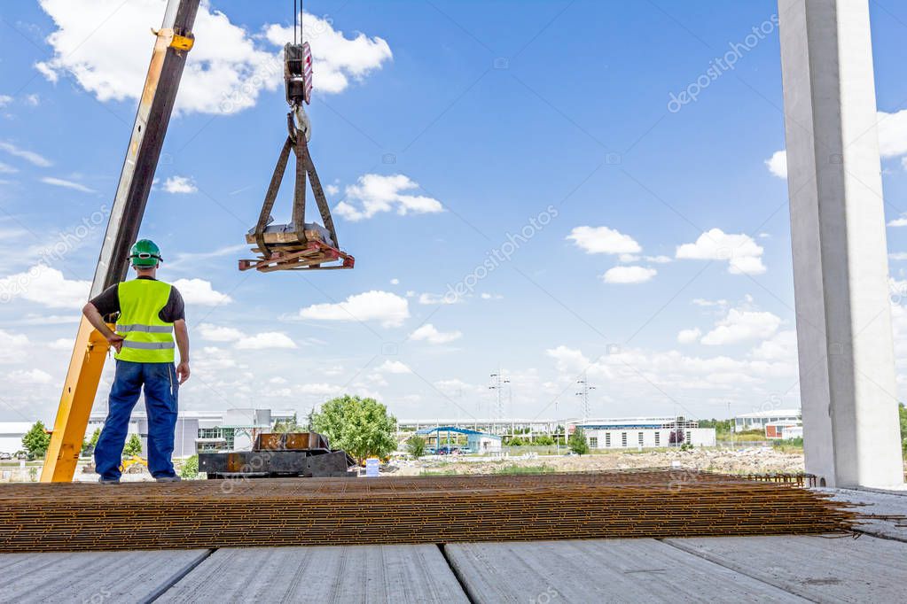 Mobile crane is lifting cargo on pallet 
