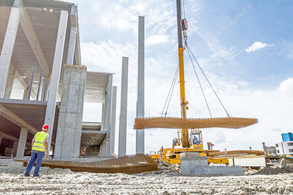 Mobile crane is carry pile of concrete armature, rusty square re