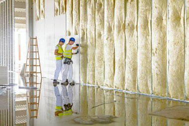 Riggers are working on thermal partition dry wall with mineral w clipart