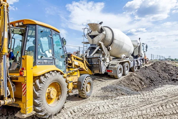 Lastbil mixer färd hälla betong i bulldozer scoop — Stockfoto