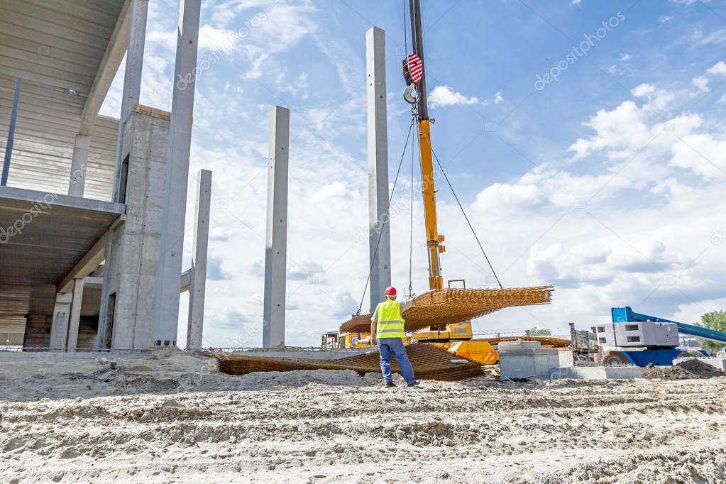 Mobile crane is carry pile of concrete armature, rusty square re