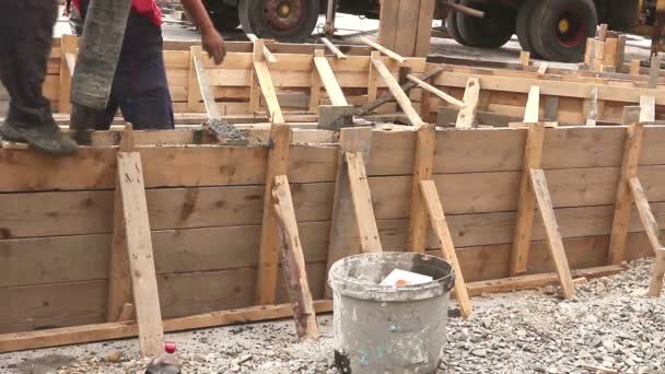 Los trabajadores están vertiendo hormigón fresco en molde de madera vertical con manguera, fundición continua — Vídeo de stock