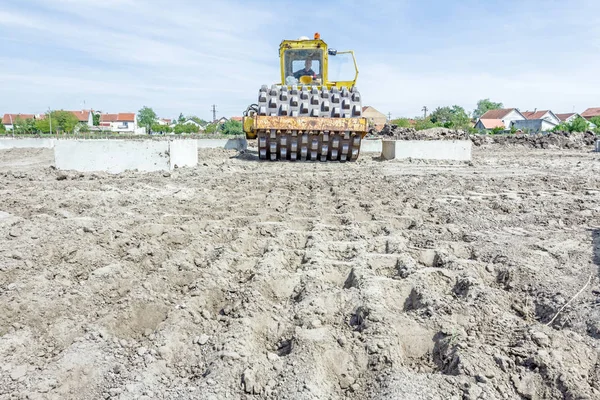 Il rullo stradale enorme con punte sta compattando il terreno all'atto di costruzione — Foto Stock