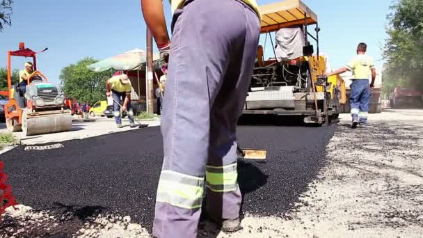 Werknemers met schoppen kómen stapel met overmaat van asfalt. — Stockvideo