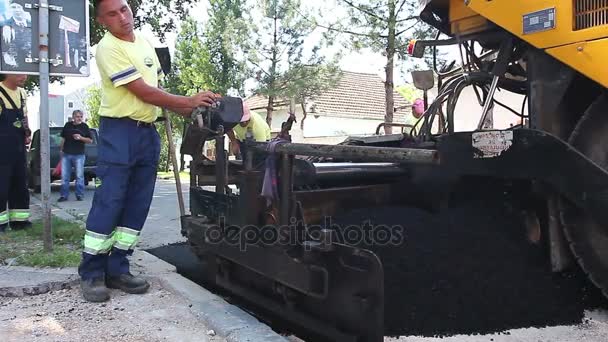 Trabalhador, o operador está controlando máquina de assentamento de estrada de asfalto com guidão, operando joystick — Vídeo de Stock