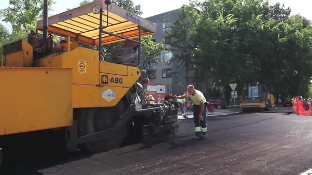 Walec jest gniecenia ziarna i rozpowszechnianie asfaltu po maszyny Rozrzutnik. — Wideo stockowe