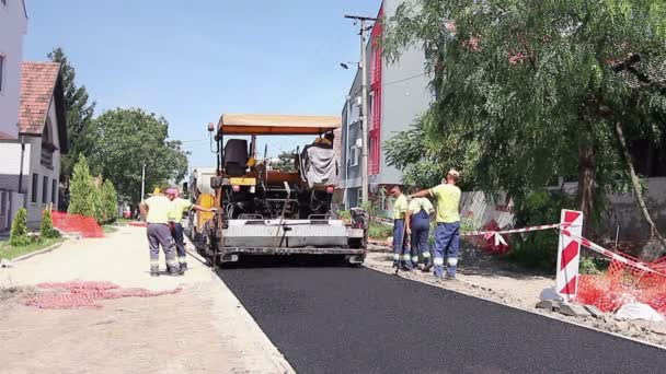 Asfalto máquina de construcción de carreteras en la actividad de construcción de carreteras. Los trabajadores están nivelando, arreglando asfalto — Vídeos de Stock