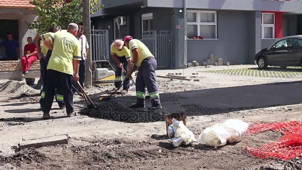 Trabalhadores estão nivelando asfalto quente depois é aplicado no chão, obras rodoviárias — Vídeo de Stock