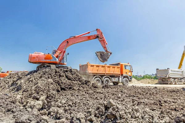 Grävmaskin laddar en lastbil på byggnadsplatsen — Stockfoto