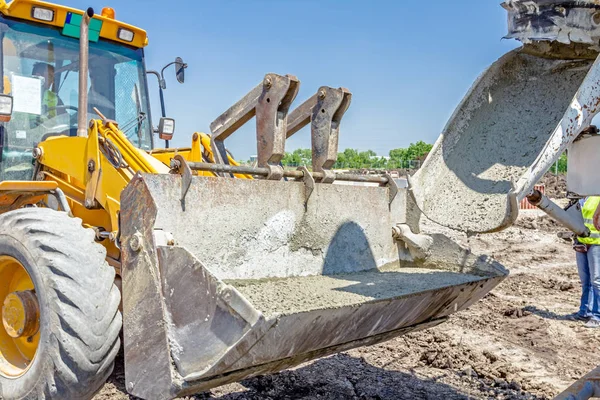 LKW-Mischer gießt Beton in Bulldozer-Schaufel. — Stockfoto